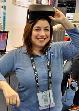 Shayna Skolnik, CEO of Navteca, poses for a picture with a virtual reality headset. Her work involves using gaming technology to help decision-makers visualize disaster risk. Credits: Marco Librero, NASA/Ames