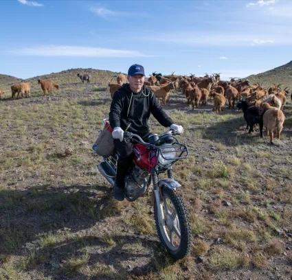 Mongolian goat herder on dirt bike