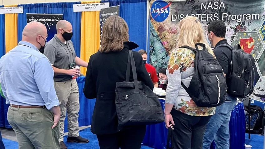 Brady Helms (second from left) and other members of NASA’s Earth Science Applied Sciences Disasters program area provide an overview of resources available to emergency managers at NASA’s exhibit booth at the 69th International Association of Emergency Managers (IAEM) Conference in Grand Rapids, Michigan, Credits: NASA/Seph Allen