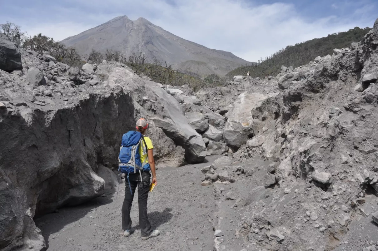 Photo of Elodie Macorps, NASA Disasters student researcher, walking toward the Colima Volcano in Mexico while conducting fieldwork for her Ph.D. in 2016. Credits: NASA / Elodie Macorps