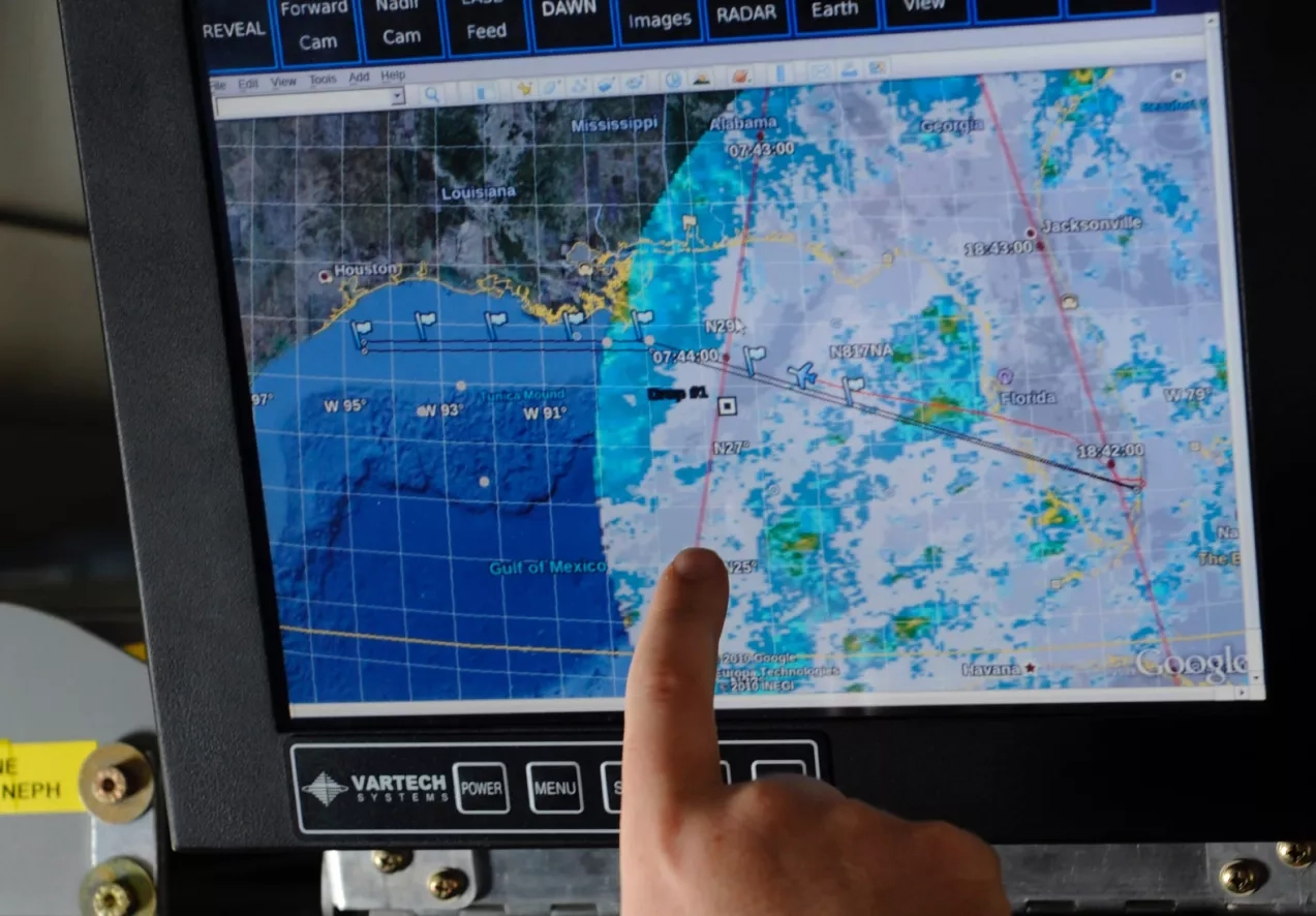 A researcher points out the trajectory of a weather pattern on a computer monitor during a flight aboard the NASA DC-8 aircraft