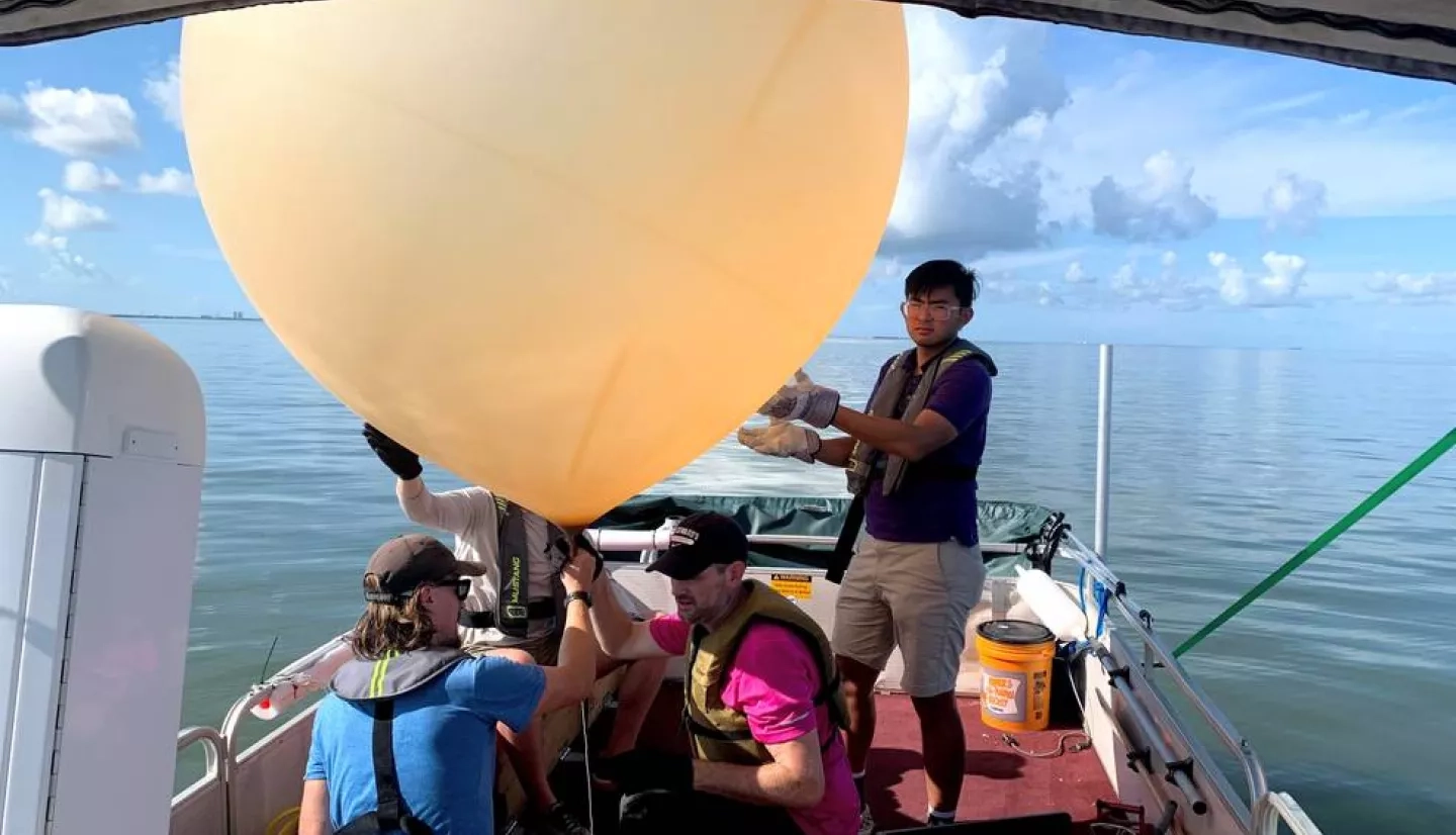 four people on boat with large research balloon