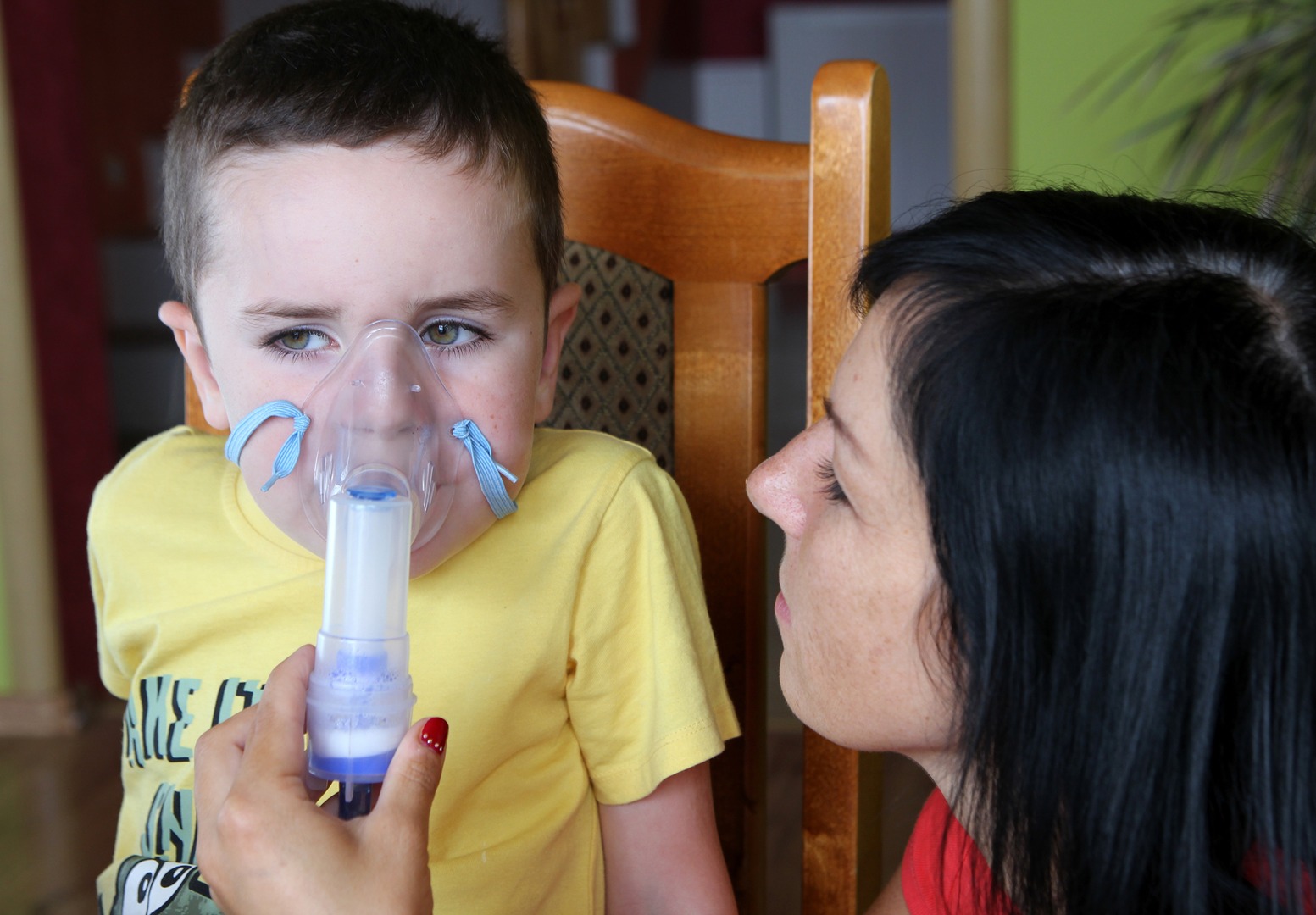woman helps child use inhaler