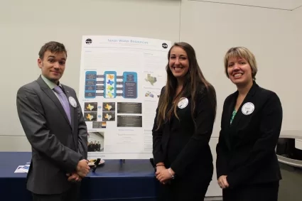 Three people stand in front of a science poster