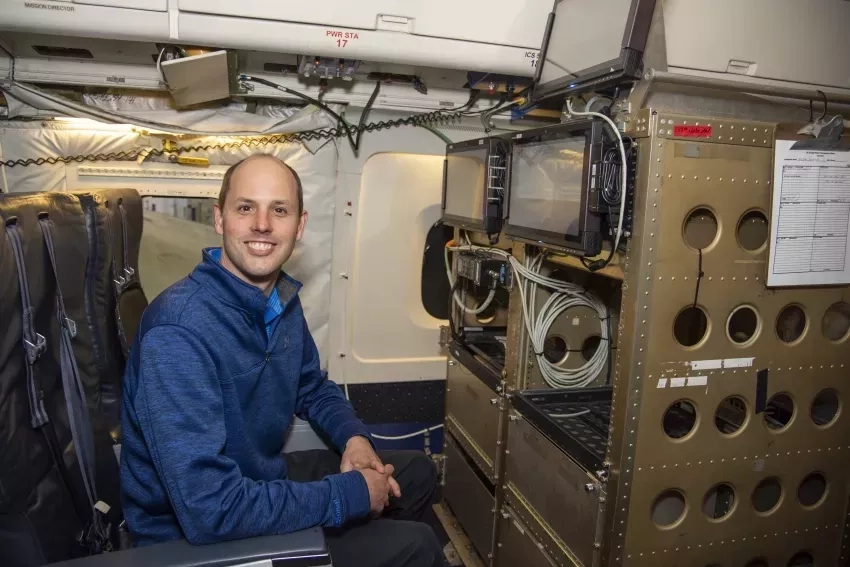 photo of man smiling at the camera near scientific equipment