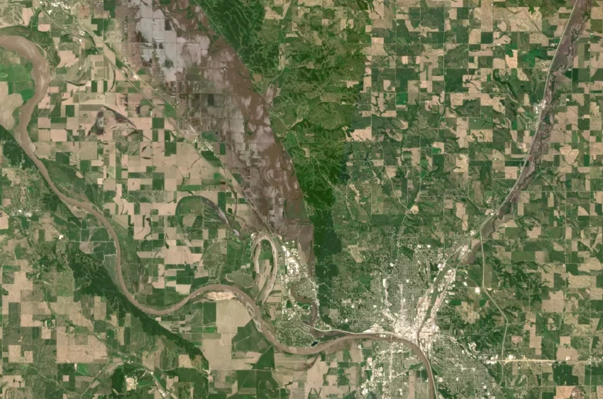 Satellite image of flooding around Sioux City, Iowa. A city is seen in the lower left, with flooded rivers and farm lands to the north and east of it. 