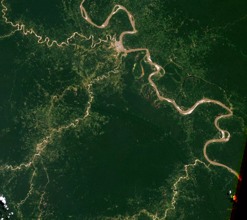 An aerial view of the Amazon captures the lush green forests with winding rivers and contrasting tan-colored roads.