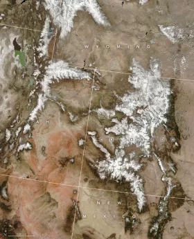 satellite image showing mostly brown landscape with stripes of white snow along mountain ranges