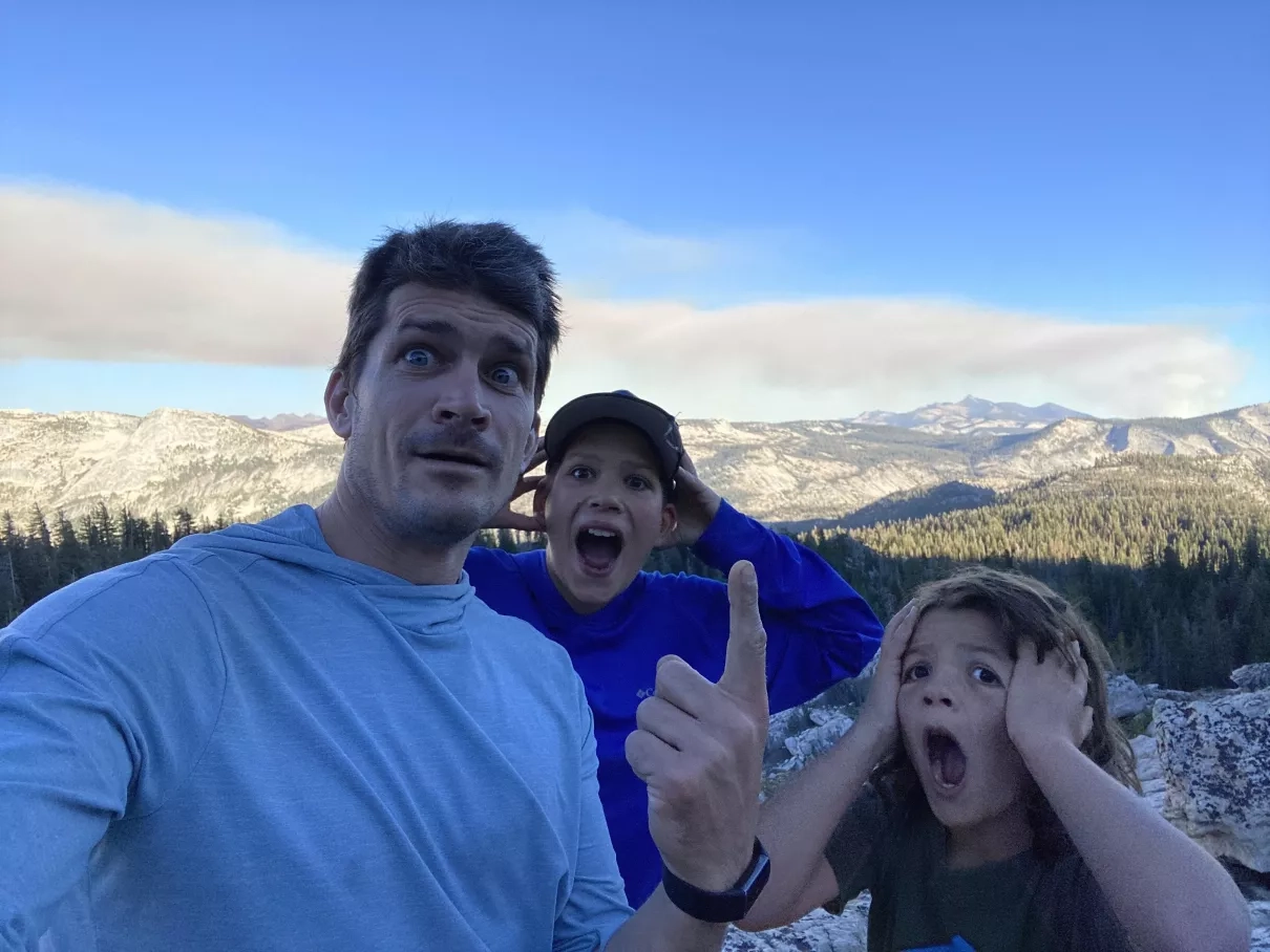From left to right, Jason, Benton, and Leo Vargo momentarily freak out after seeing the smoke plume from the Red Fire in Yosemite National Park, seen from May Lake on August 12, 2022. Credits: NASA/Jason Vargo