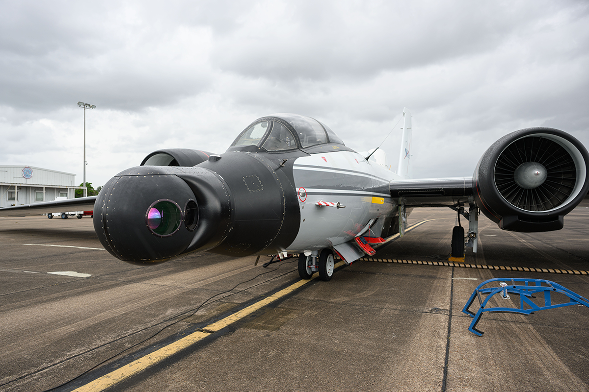  NASA's WB-57 aircraft prepares for takeoff on the runway under a cloudy sky. The spherical DyNAMITE camera is prominently shown attached to the nosecone. 