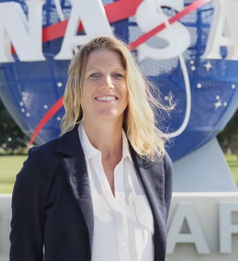 blonde woman smiling in front of NASA logo