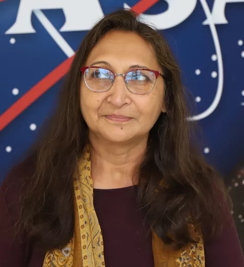 Amita pictured standing in front of the original NASA logo