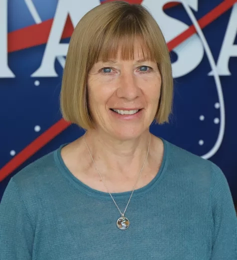 Photo of Annelise Carleton-Hug in front of the original NASA logo