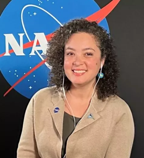 Natasha Sadoff pictured in front of a black backdrop with the NASA logo
