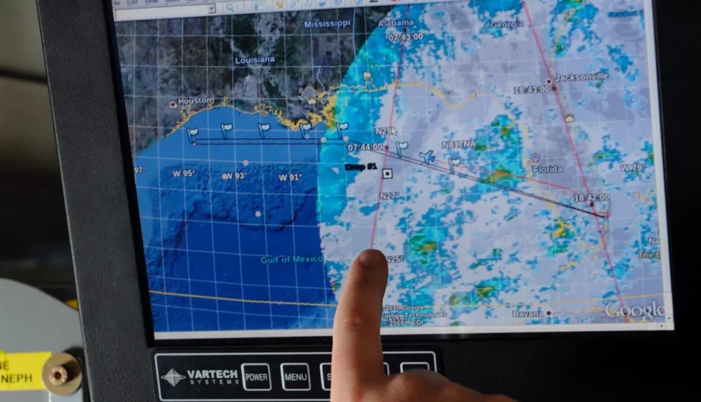 A researcher points out the trajectory of a weather pattern on a computer monitor during a flight aboard the NASA DC-8 aircraft