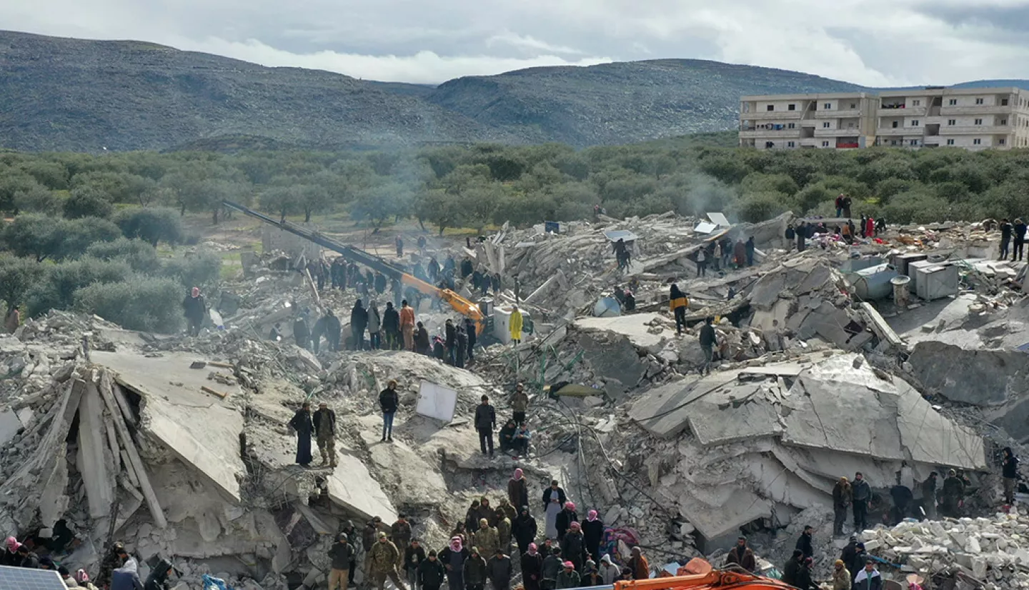 Photograph of rubble and destroyed buildings in the aftermath of the 2023 Turkiye earthquakes, with rescue workers and examining the wreckage. 