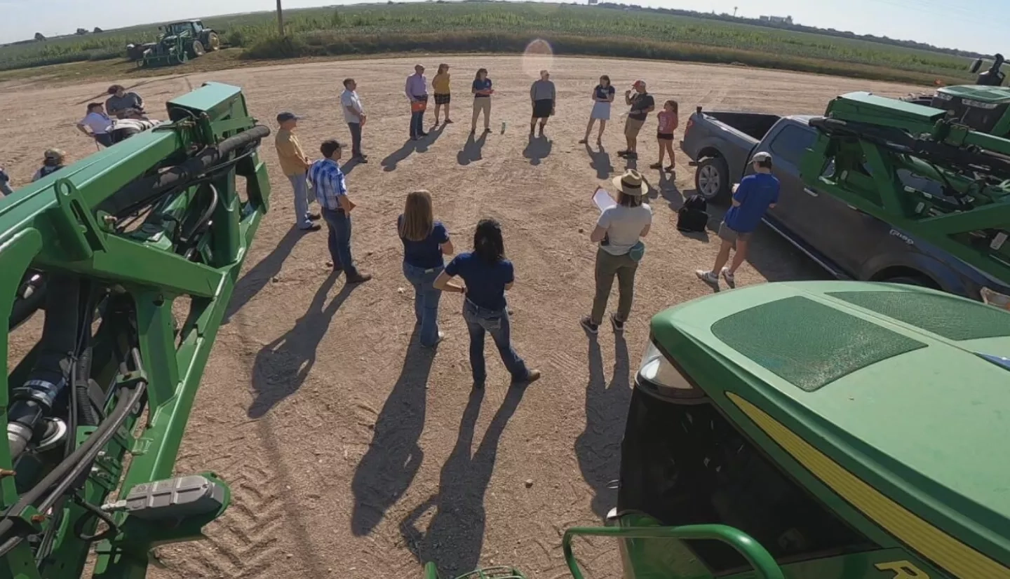 view from a high vantage point of a group of people standing near tractors in a field