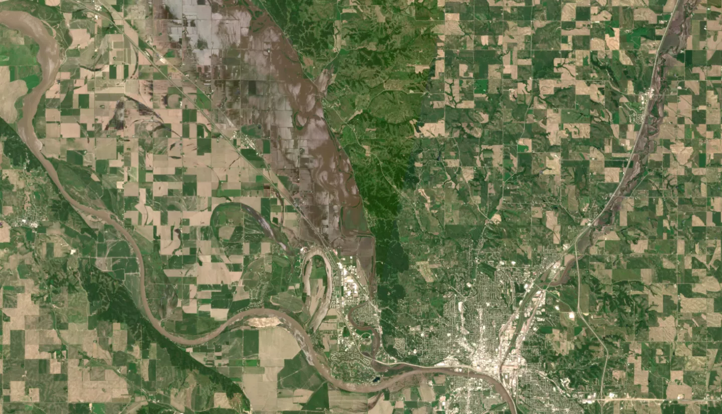 Satellite image of flooding around Sioux City, Iowa. A city is seen in the lower left, with flooded rivers and farm lands to the north and east of it. 