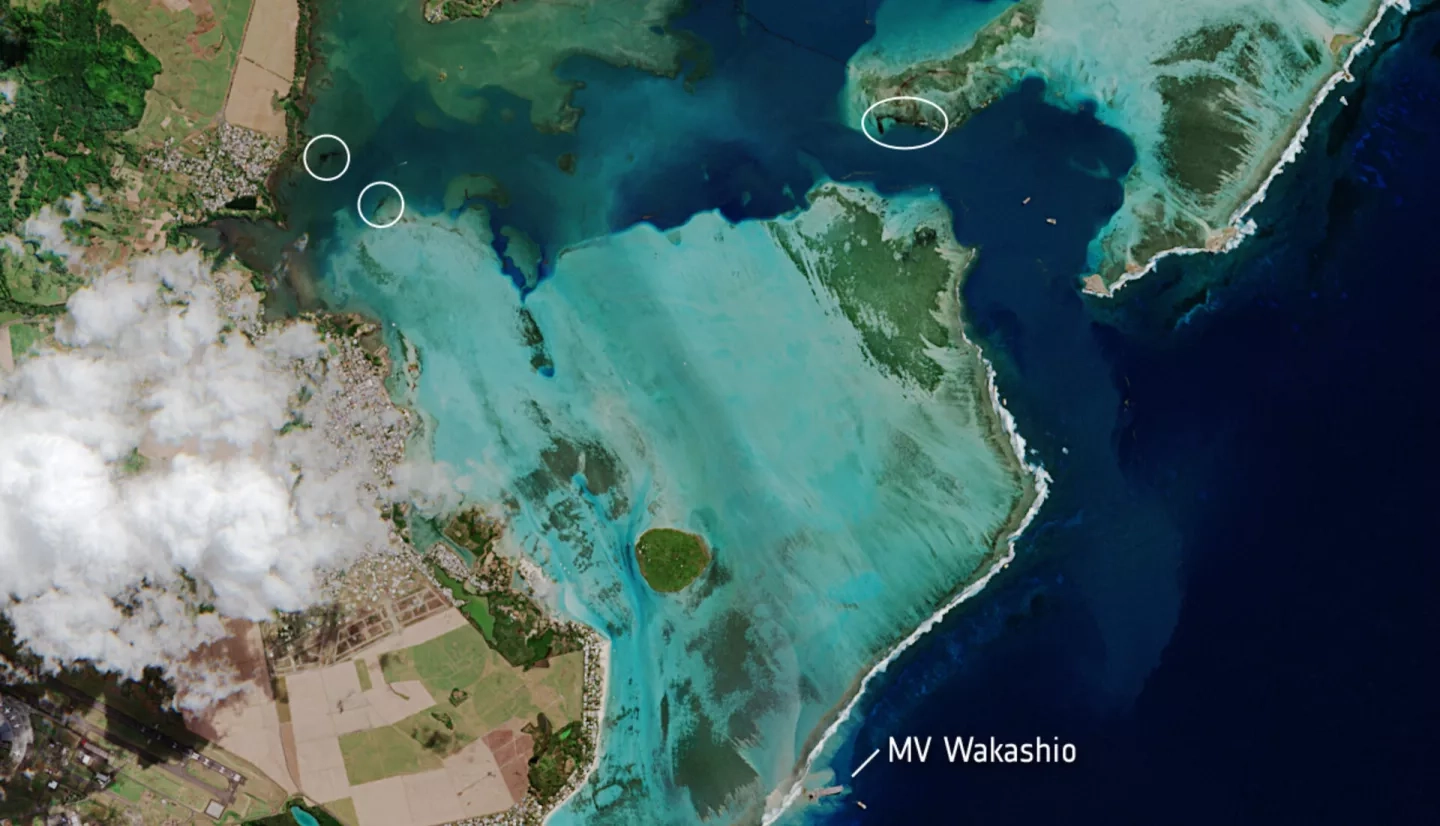 In this image, captured on August 11th, 2020, by the European Space Agency (ESA) Copernicus Sentinel-2 satellite mission, the MV Wakashio oil tanker, visible in the bottom of the image, is stranded close to the wetland area of Pointe d’Esny. Spilled oil is circled in this image. It is also visible as a labeled thin, black line near the top of the image. Credit: Contains modified Copernicus Sentinel data (2020), processed by ESA