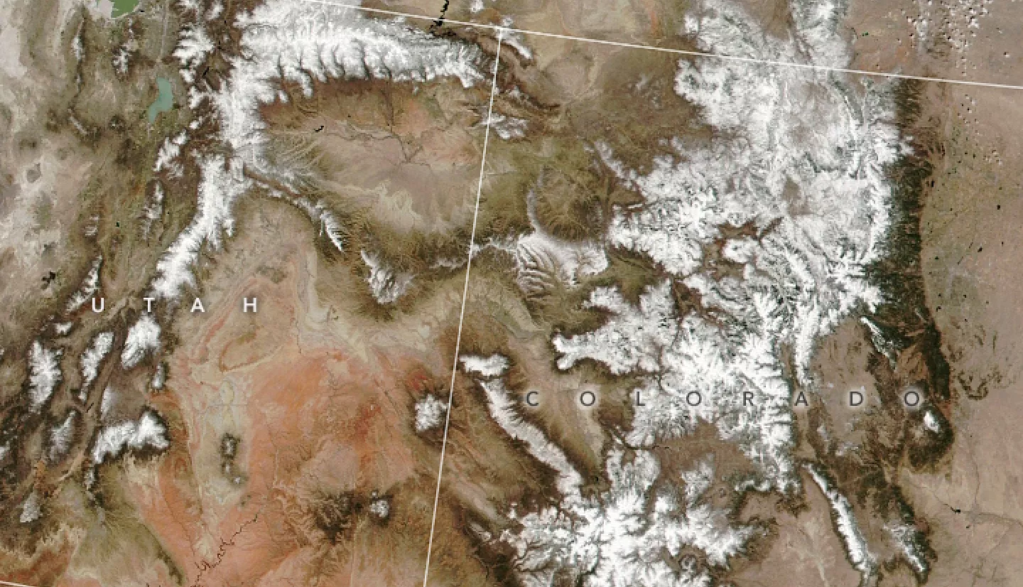 satellite image showing mostly brown landscape with stripes of white snow along mountain ranges