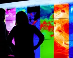 NASA scientists silhouette in front of a Hyperwall visualization of air quality data 
