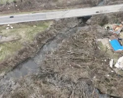 Aerial photo of downed trees and houses with blue tarps from tornado damage.