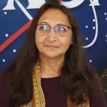 Amita pictured standing in front of the original NASA logo