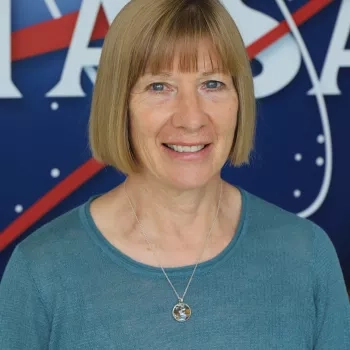 Photo of Annelise Carleton-Hug in front of the original NASA logo