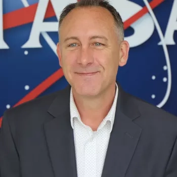 Image of Brock in front of the original NASA logo