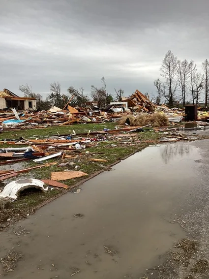 Destroyed houses and rubble under a cloudy sky. 